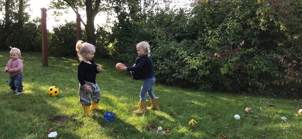 Børn spiller bold i have
