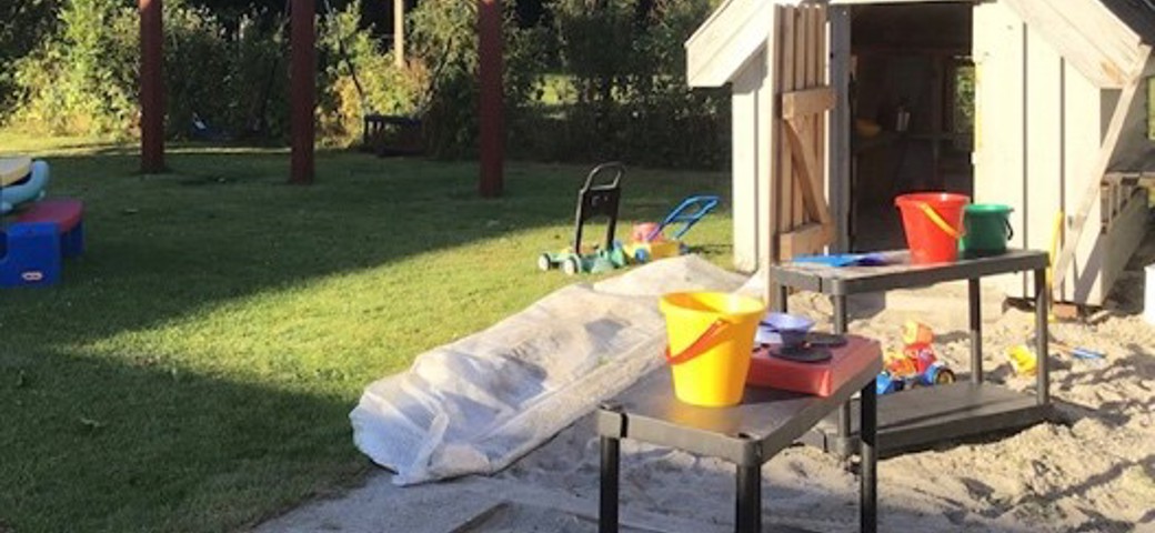 Legehus med legesager og gynge i baggrunden