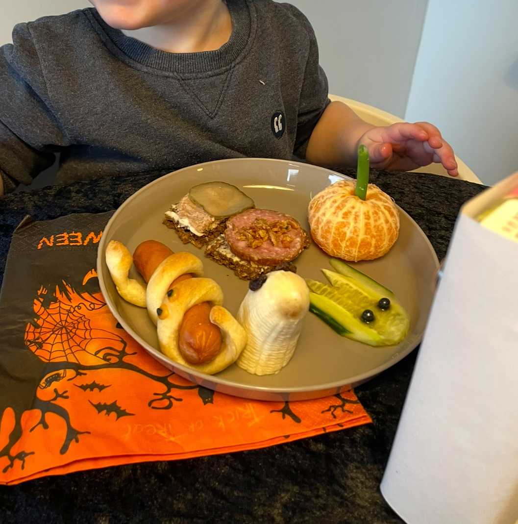 Tallerken med rugbrødsmadder samt frugt og pølehorn pyntet så de ligner små dyr. 
