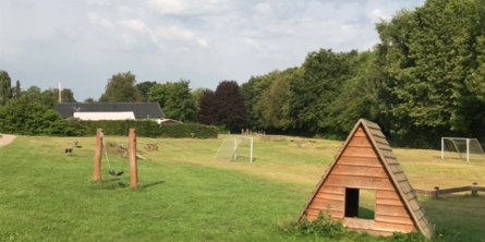 grønt område med legehus, gynger og fodboldmål